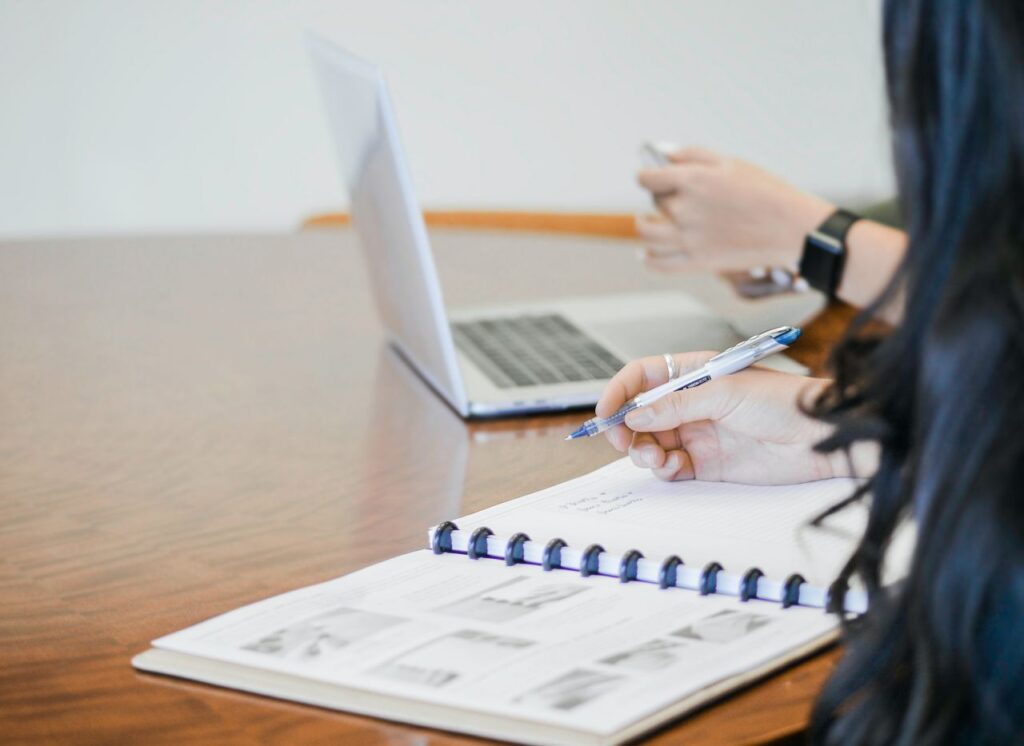 woman taking notes and listening to man using laptop